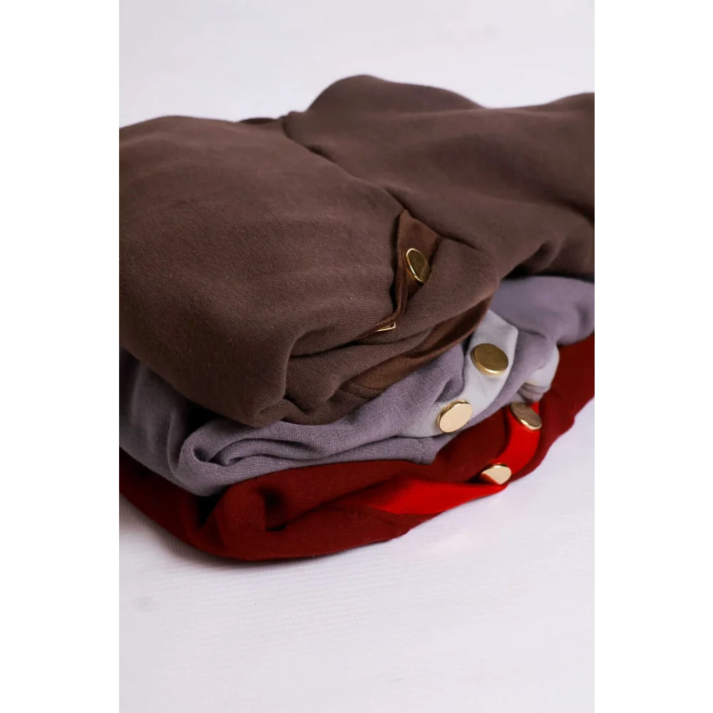 Stack of folded bluza lara garments with mikropolarem alpejskim in earthy tones featuring gold button accents