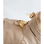 Gold-tone metal zipper pull with textured leather finish and white fabric loop on beige kombinezon dla psa with fur lining