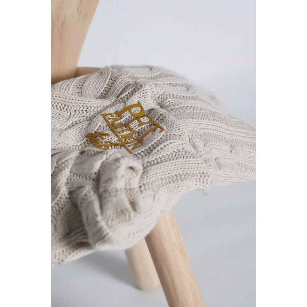 Cream-colored sweterek wełniany dla psa with gold embroidered logo patch that chroni szyję pupila