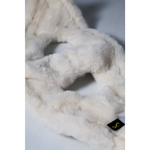 A plush off-white faux fur headband with a soft texture and a black tag featuring a gold s logo for szelki bezuciskowe with okucia pokryte 24k złotem