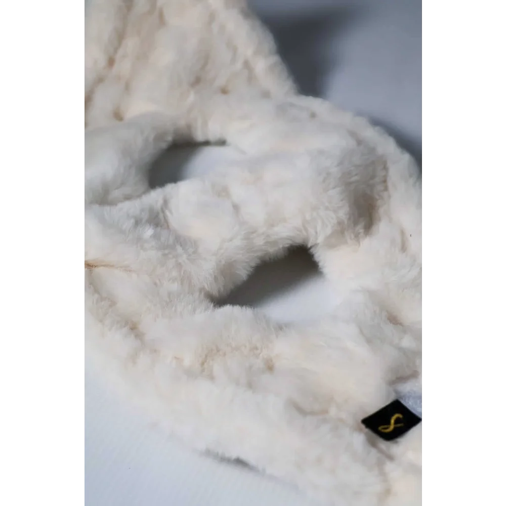 A plush off-white faux fur headband with a soft texture and a black tag featuring a gold s logo for szelki bezuciskowe with okucia pokryte 24k złotem
