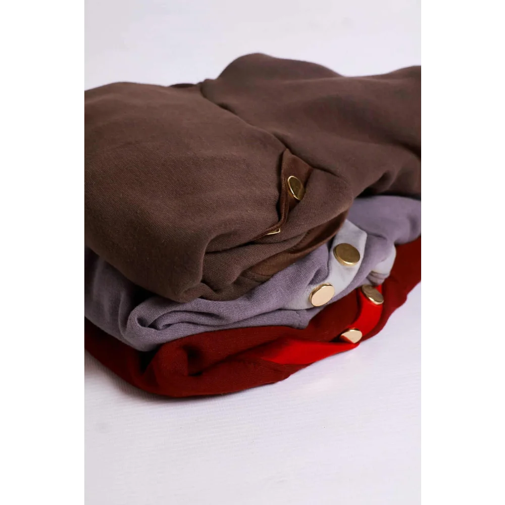 Stack of folded bluza dla psa in gray with mikropolarem alpejskim and gold-toned buttons visible on garments