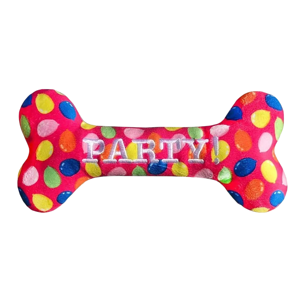 Wibrujący różowy pluszowy piesek w kształcie kości, ozdobiony kolorowymi grochami i wyszyty słowem ’party!’ białymi literami.