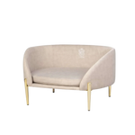 Beżowa aksamitna sofa dla zwierząt z nogami z metalu w złotym kolorze.