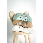 Stacked on a wooden stool are szelki bezuciskowe dog harnesses with miękka futrzana podszewka in mint green gold and white