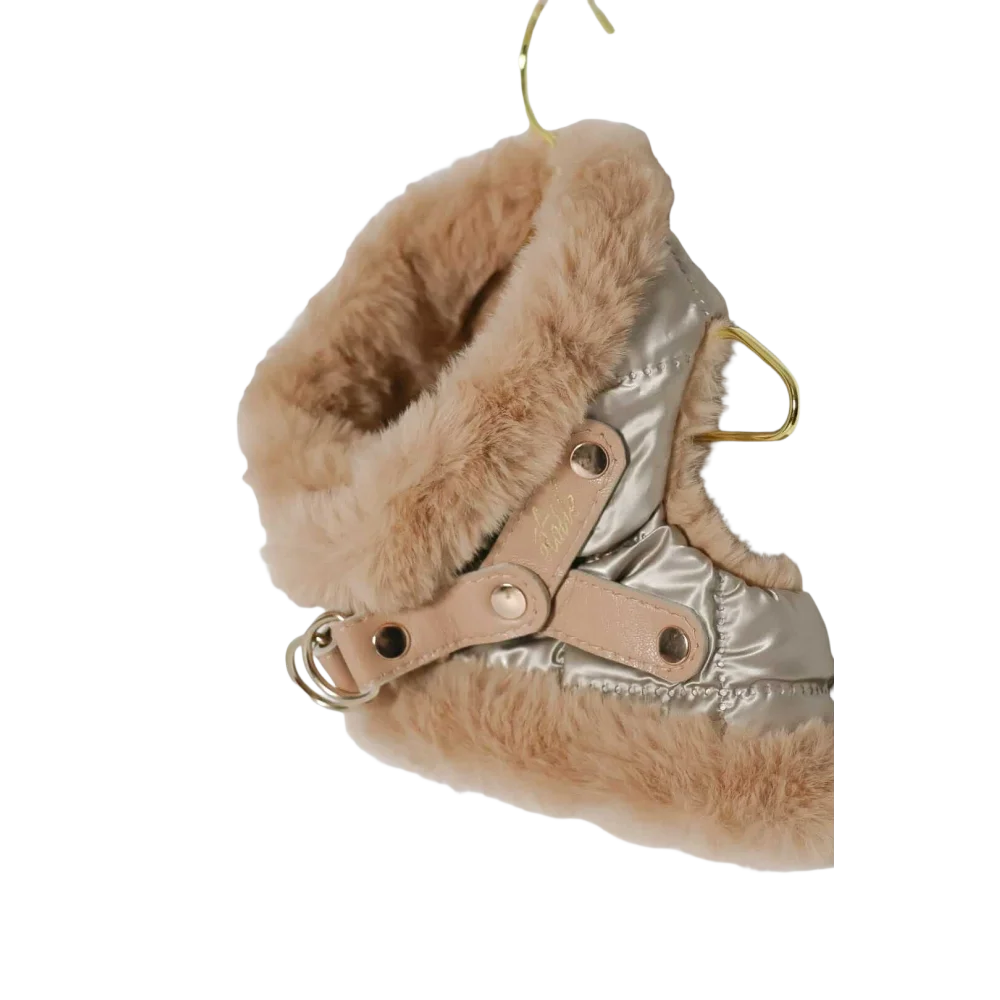 A cozy metallic silver bezrękawnik puchowy dla psa with plush tan fur trim and light brown leather straps for obwód szyi adjustment